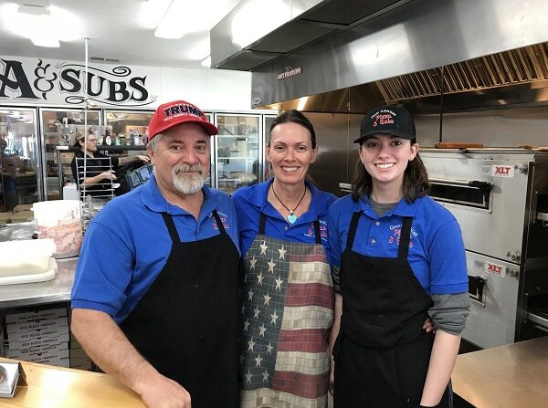 (De izquierda a derecha) Robert Hall, Kathleen Hall y su hija Gabriella posan en su restaurante, Great American Pizza and Subs, en Golden Valley, Arizona, el 24 de febrero de 2022. (NTD)