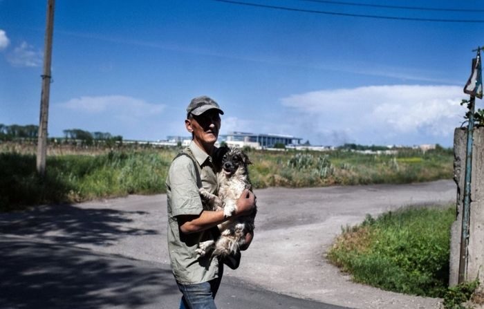 Un hombre lleva un perro mientras se aleja de una zona cercana al aeropuerto internacional de Donetsk durante un intenso tiroteo entre el ejército ucraniano y los militantes prorrusos en la ciudad de Donetsk, en el este de Ucrania, el 26 de mayo de 2014. (DIMITAR DILKOFF/AFP via Getty Images)