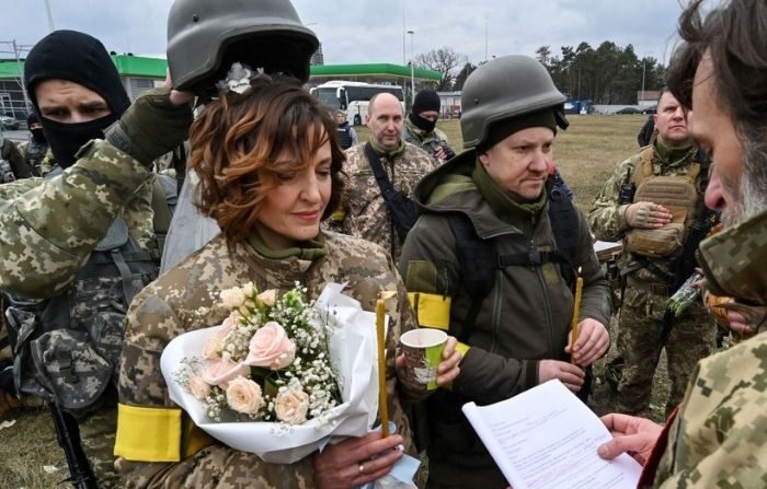 Los soldados de la defensa territorial ucraniana, Valery (I) y Lesya (D), se casan cerca del puesto de control en las afueras de Kiev el 6 de marzo de 2022. (GENYA SAVILOV/AFP vía Getty Images)