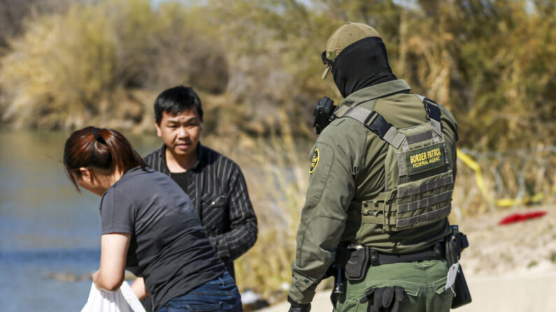 Un agente de la Patrulla Fronteriza detiene a una pareja china que acaba de cruzar el Río Grande desde México hasta Eagle Pass, Texas, el 25 de enero de 2022. (Charlotte Cuthbertson/The Epoch Times)