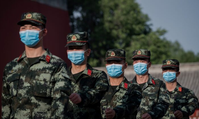 Soldados del Ejército Popular de Liberación (EPL) de China marchan junto a la entrada de la Ciudad Prohibida (iz) en Beijing el 22 de mayo de 2020. (NICOLAS ASFOURI/AFP vía Getty Images)