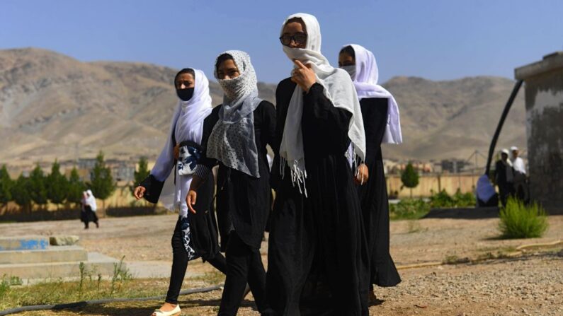 Niñas afganas se cubren la cara con pañuelos mientras caminan dentro del recinto de su escuela tras su reapertura, que antes estaba cerrada debido a la pandemia de COVID-19, en Herat el 23 de agosto de 2020. (Hoshang Hashimi/AFP vía Getty Images)