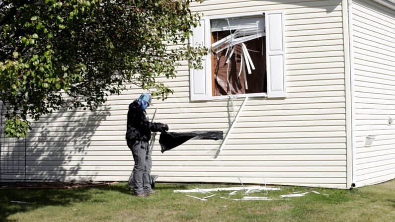 Una persona limpia los escombros de una ventana rota en una casa que los agentes del FBI registraron en el parque de casas móviles de Hartland Township la noche del miércoles y hasta la mañana del jueves en relación con un complot para secuestrar a la gobernadora de Michigan, Gretchen Whitmer, el 8 de octubre de 2020 en Heartland, Michigan. (JEFF KOWALSKY/AFP vía Getty Images)