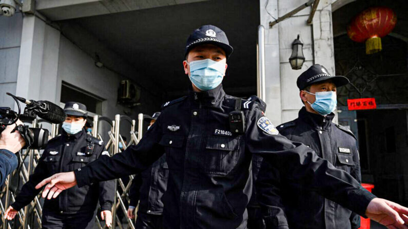 Policías aseguran una entrada lateral tras la llegada de vehículos policiales al Tribunal Popular Intermedio de Dandong, en la provincia nororiental china de Liaoning, el 19 de marzo de 2021. (Noel Celis/AFP vía Getty Images)