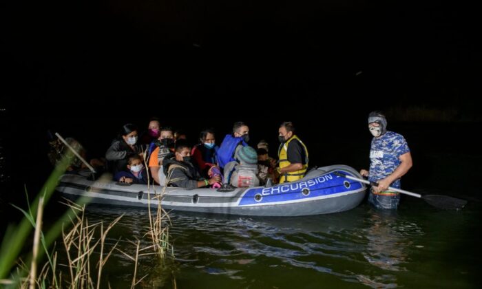 Un coyote contrabandista de personas (D) guía un bote inflable que transporta a los migrantes de América Central que llegan ilegalmente desde México a EE.UU. para pedir asilo, en el río Grande en la ciudad fronteriza de Roma, Texas, el 29 de marzo de 2021. (Ed Jones/AFP vía Getty Images)