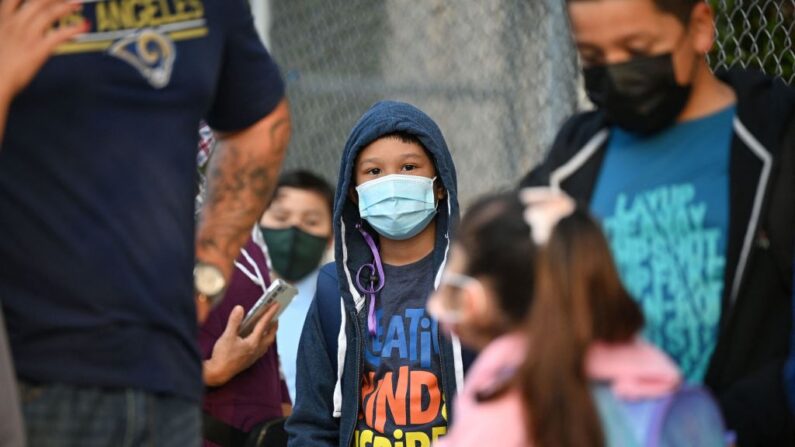 Alumnos y padres con el rostro cubierto esperan en la fila para el primer día del año escolar en la escuela primaria Grant en Los Ángeles, California, el 16 de agosto de 2021. (Robyn Beck/AFP vía Getty Images)