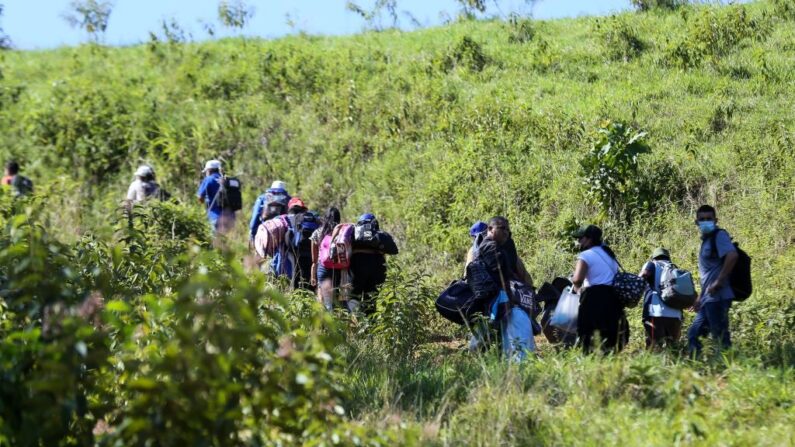 Migrantes que quieren llegar a Estados Unidos, en su mayoría hondureños y nicaragüenses, cruzan de Honduras a Guatemala a través de un sendero ilegal, en Corinto, Honduras, el 15 de enero de 2022. (WENDELL ESCOTO/AFP vía Getty Images)