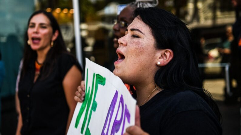 La gente sostiene pancartas y grita consignas mientras protesta frente a la oficina de la senadora estatal de Florida Ileana Garcia en Coral Gables, Florida, el 9 de marzo de 2022. (CHANDAN KHANNA/AFP vía Getty Images)