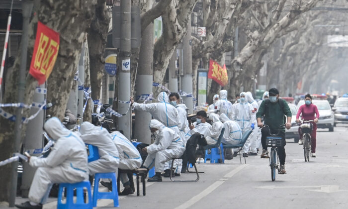Trabajadores con ropa de protección se encuentra junto a algunas zonas de cierre porCOVID-19 en Shanghái el 14 de marzo de 2022, tras la detección de nuevos casos de infección. (Hector Retamal/AFP vía Getty Images)