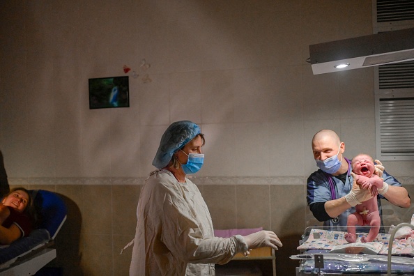 Enfermeros atienden a un bebé en una sala de maternidad mientras las sirenas anuncian ataques aéreos en Mykolaiv, el 14 de marzo de 2022. (BULENT KILIC/AFP vía de Getty Images)