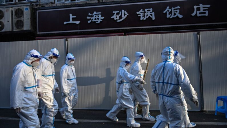 Trabajadores con ropa de protección en una zona donde se están colocando barreras para cerrar las calles alrededor de las zonas de confinamiento tras la detección de nuevos casos de COVID-19 en Shanghai el 15 de marzo de 2022. (Hector Retamal/AFP vía Getty Images)