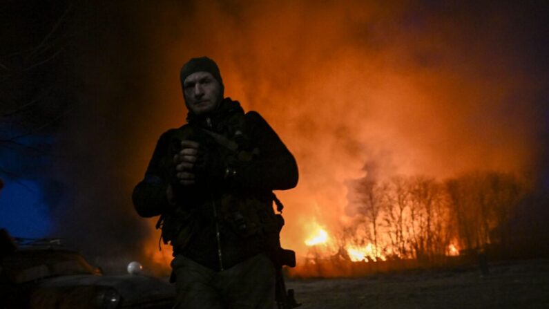 Un militar ucraniano de pie frente a un almacén en llamas luego de un bombardeo en Kiev el 17 de marzo de 2022. (Aris Messinis/AFP a través de Getty Images)
