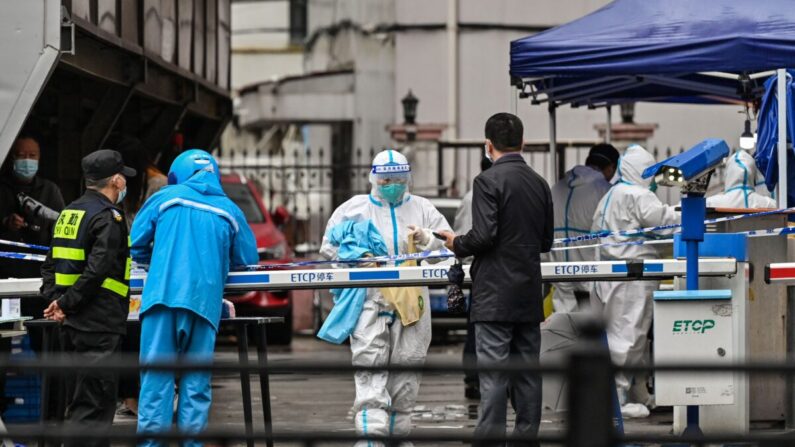 Un repartidor (L en azul) es visto llegando a entregar un pedido fuera de un barrio cerrado tras la detección de nuevos casos de COVID-19 en el distrito de Huangpu, en Shanghai el 17 de marzo de 2022. (Hector Retamal/AFP vía Getty Images)