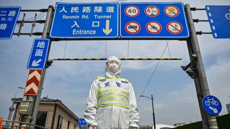 Un agente de tránsito, con equipo de protección, controla el acceso a un túnel en dirección al distrito de Pudong en cierre como medida contra el coronavirus COVID-19, en Shanghai el 28 de marzo de 2022. (Hector Retamal/AFP vía Getty Images)
