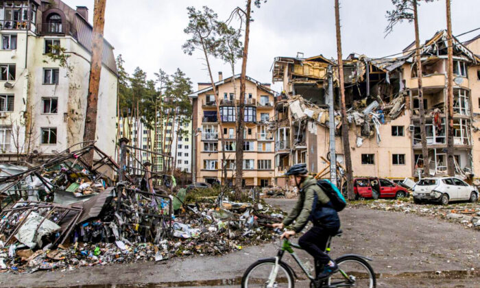 Un hombre pasa con su bicicleta por delante de edificios destruidos en Irpin, Ucrania, el 3 de marzo de 2022. (Chris McGrath/Getty Images)