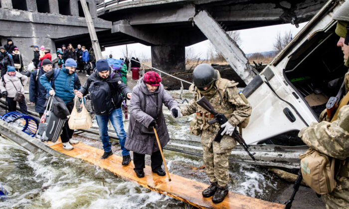 Los residentes de Irpin, Ucrania, huyen de los intensos combates a través de un puente destruido cuando las fuerzas rusas entraron en la ciudad el 7 de marzo de 2022. (Chris McGrath/Getty Images)