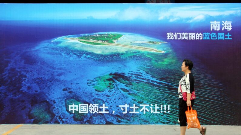 Una mujer pasa junto a un cartel del mar de China Meridional, con el lema en la parte inferior "Territorio de China, nunca cederemos ni un centímetro de nuestro terreno" en una calle de Weifang, provincia oriental china de Shandong, el 14 de julio de 2016. (STR/AFP/Getty Images)