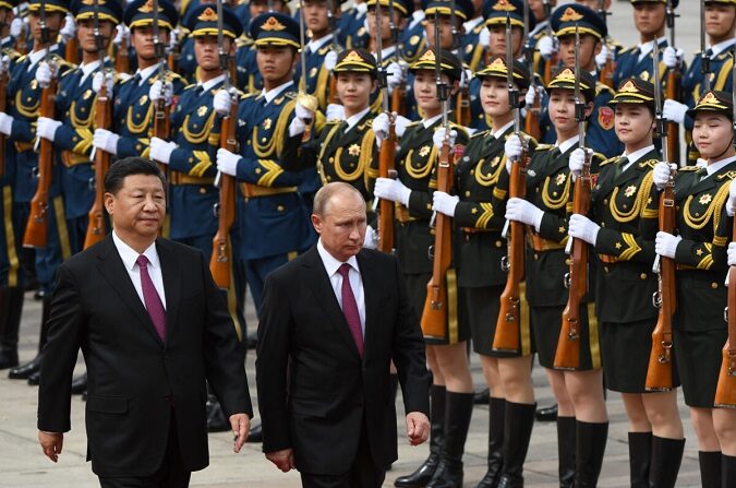 El presidente de Rusia, Vladimir Putin (C), pasa revista a una guardia de honor militar junto al presidente chino, Xi Jinping (I), durante una ceremonia de bienvenida frente al Gran Salón del Pueblo en Beijing, el 8 de junio de 2018. (Greg Baker/POOL/AFP vía Getty Images)