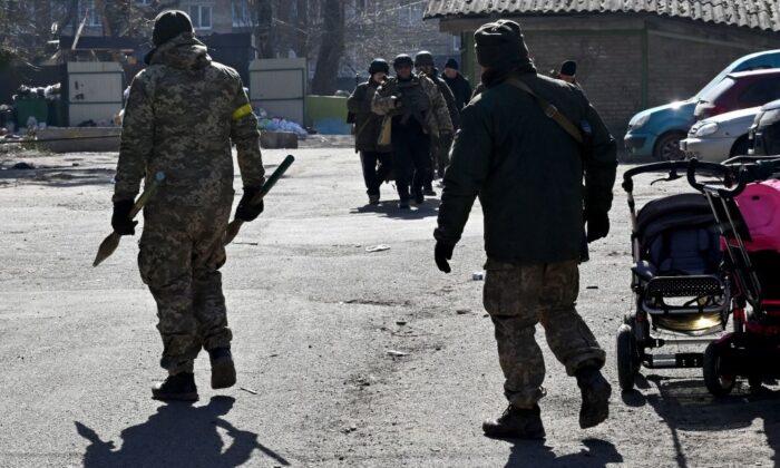 Un soldado ucraniano (Izq.) lleva granadas propulsadas por cohetes (RPG) junto a cochecitos e bebé abandonados en Irpin, al norte de Kiev, Ucrania, el 12 de marzo de 2022. (Sergei Supinsky/AFP a través de Getty Images)