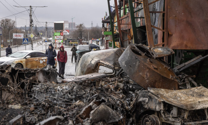 Algunas personas pasan por delante de un vehículo militar ruso destruido en una posición de primera línea en Irpin, Ucrania, el 3 de marzo de 2022. (Chris McGrath/Getty Images)