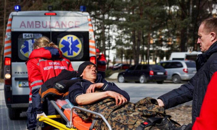 Un hombre herido en ataques aéreos en un complejo militar cercano es asistido por personal médico fuera del Hospital del Distrito de Novoiavorivsk en Novoiavorivsk, Ucrania, el 13 de marzo de 2022. (Dan Kitwood/Getty Images)