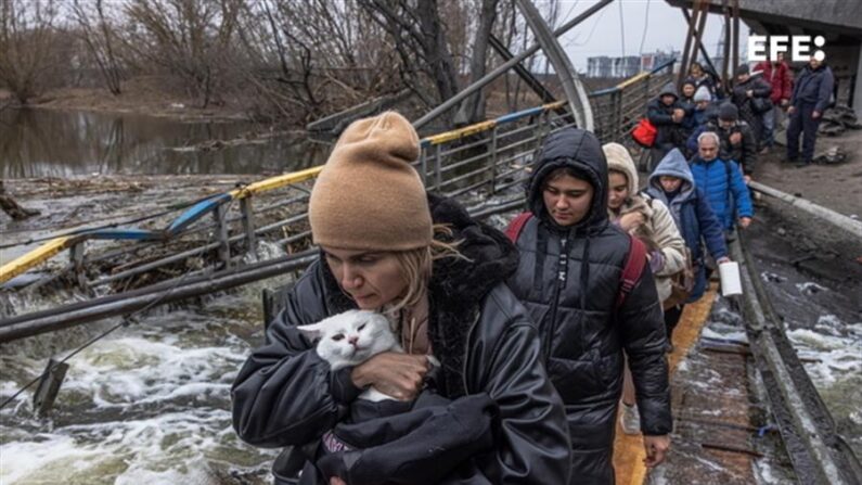  Una mujer con su gato cruza un puente destruido en la ciudad de Irpín, cerca de Kiev, el 7 de marzo de 2022. (EFE/ Roman Pilipey)