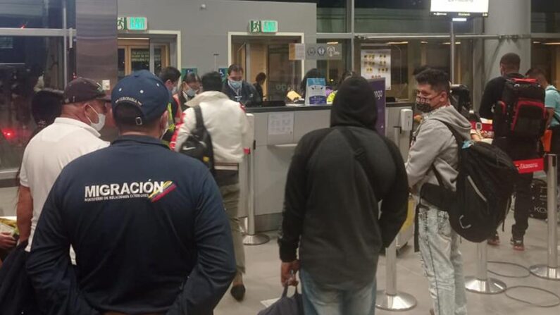 Fotografía cedida el 28 de marzo de 2022 por Migración Colombia que muestra a un oficial de la autoridad migratoria mientras acompaña a un grupo de ciudadanos cubanos en el Aeropuerto Internacional El Dorado de Bogotá (Colombia). EFE/Migración Colombia