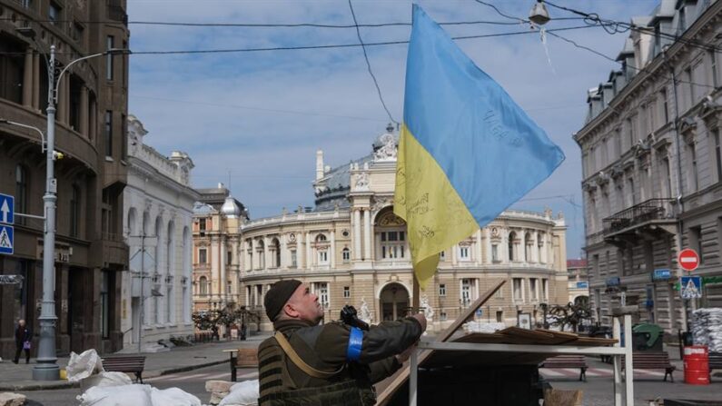 Un soldado ucraniano cuelga una bandera ucraniana junto a una barricada en la ciudad de Odesa, en el sur de Ucrania, el 21 de marzo de 2022. (EFE/EPA/SEDAT SUNA)