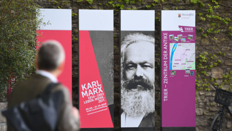 Un hombre pasa por delante de los tableros que celebran los 200 años del nacimiento de Karl Marx en Tréveris, Alemania, el 3 de mayo de 2018. (Foto de Patrik Stollarz/AFP vía Getty Images)