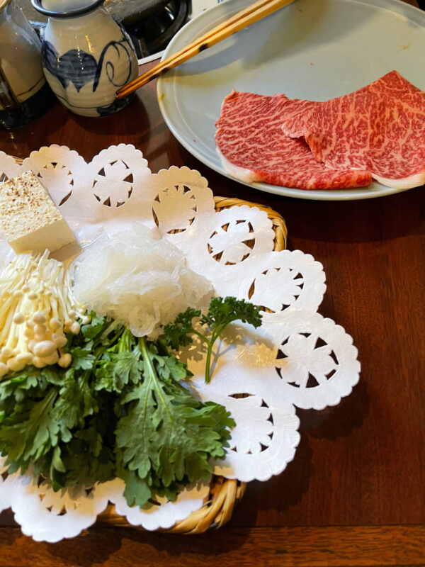 Platos de carne de vaca ricamente adobada, verduras de crisantemo, fideos, setas y tofu. (Melissa Uchiyama)