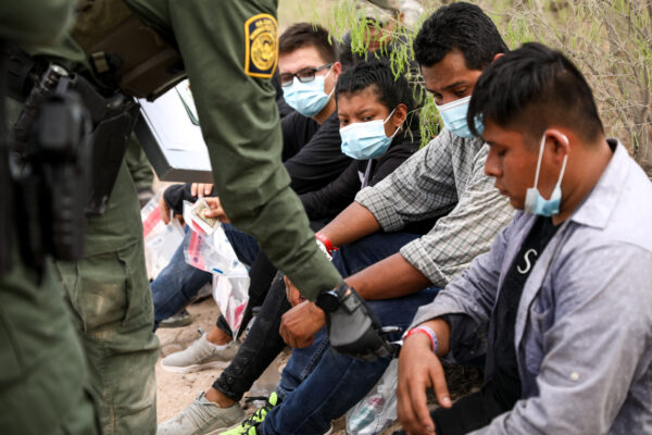 Un agente de la Patrulla Fronteriza revisa a un inmigrante ilegal que lleva dos muñequeras que los cárteles mexicanos han estado usando para controlar el contrabando de personas a Estados Unidos, cerca de Peñitas, Texas, el 15 de marzo de 2021. (Charlotte Cuthbertson/The Epoch Times)
