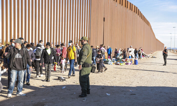 Un agente de la Patrulla Fronteriza organiza a inmigrantes ilegales reunidos junto a la valla fronteriza después de cruzar de México a Estados Unidos, en Yuma, Arizona, el 10 de diciembre de 2021. (Charlotte Cuthbertson/The Epoch Times)
