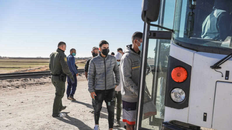 Los inmigrantes ilegales que se han reunido junto al muro fronterizo suben a un autobús que se dirige a la estación de la Patrulla Fronteriza para su procesamiento en Yuma, Arizona, el 10 de diciembre de 2021. (Charlotte Cuthbertson/The Epoch Times)
