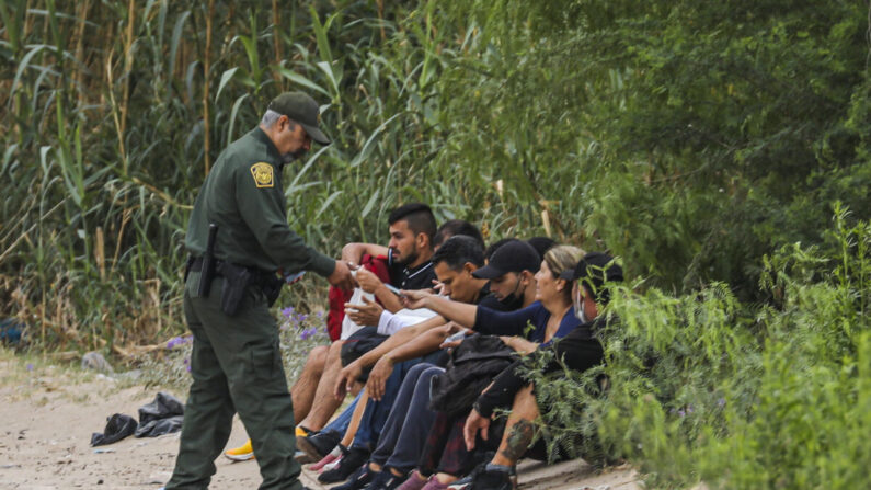Un agente de la Patrulla Fronteriza detiene a un grupo de cubanos que acaba de cruzar el Río Grande desde México hacia Eagle Pass, Texas, el 19 de abril de 2022. (Charlotte Cuthbertson/The Epoch Times)
