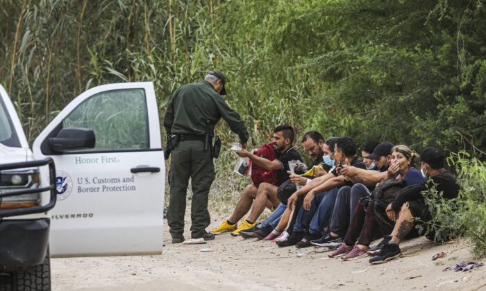Un agente de la Patrulla Fronteriza detiene a un grupo de cubanos que acababan de cruzar el Río Grande desde México hacia Eagle Pass, Texas, el 19 de abril de 2022. (Charlotte Cuthbertson/The Epoch Times)
