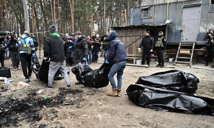 Trabajadores municipales transportan bolsas de cadáveres con seis cuerpos parcialmente quemados encontrados en la ciudad de Bucha, Ucrania, el 5 de abril de 2022. (Genya Savilov/AFP vía Getty Images)