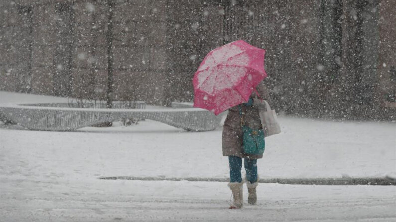 Fotografía de archivo de una mujer cruzando una calle durante una tormenta de nieve en Estados Unidos. EFE/ Jason Szenes