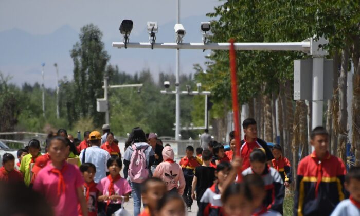 Escolares caminan debajo de las cámaras de vigilancia en Akto, al sur de Kashgar, en la región occidental china de Xinjiang, el 4 de junio de 2019. (Greg Baker/AFP a través de Getty Images)
