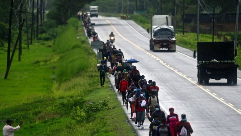 Un hombre (i) saluda a los migrantes que se dirigen en caravana a la frontera con Guatemala por la carretera Panamericana en Cerro de Hula, 10 km al sur de Tegucigalpa (Honduras), el 3 de junio de 2020. (Orlando Sierra/AFP vía Getty Images)