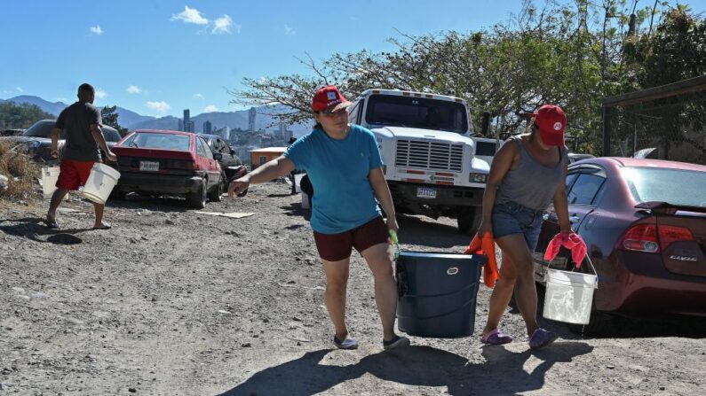La gente lleva cubos con agua después de obtener agua potable de un camión cisterna en las afueras de Tegucigalpa (Honduras) el 22 de marzo de 2022. (Orlando Sierra/AFP vía Getty Images)