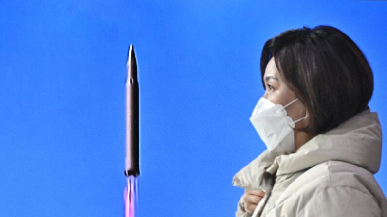 Una mujer pasa junto a un informe de televisión que muestra un noticiero con imágenes de archivo de una prueba de misiles de Corea del Norte, en una estación de tren en Seúl el 24 de marzo de 2022.  (Anthony Wallace / AFP vía Getty Images)