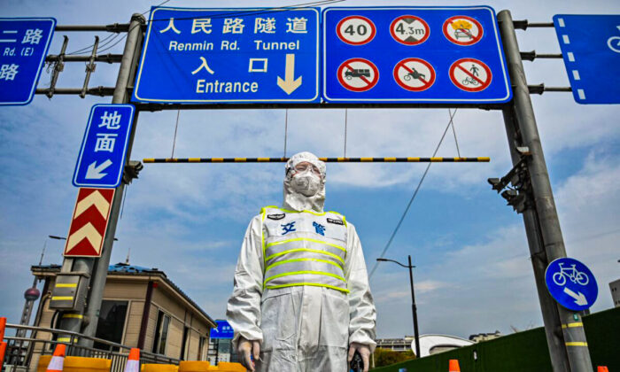 Un agente de tránsito, con un equipo de protección, controla el acceso a un túnel en dirección al distrito de Pudong de Shanghái en cierre el 28 de marzo de 2022.(Hector Retamal/AFP via Getty Images)