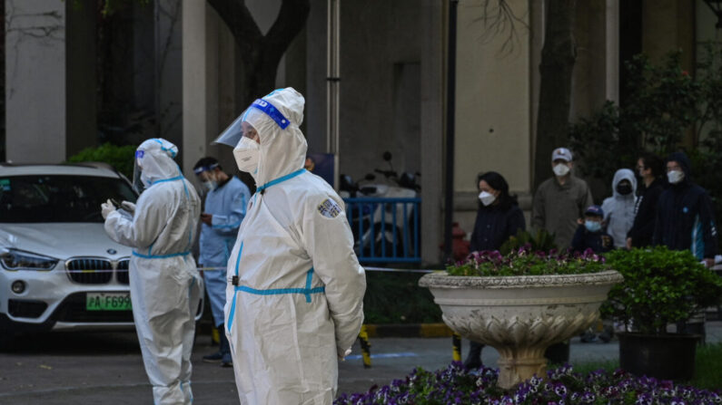 Trabajadores y voluntarios observan en un recinto donde los residentes son sometidos a pruebas de COVID-19 durante la segunda etapa de un confinamiento por la pandemia en el distrito de Jing'an en Shanghai, China, el 4 de abril de 2022. (Hector Retamal/AFP vía Getty Images)