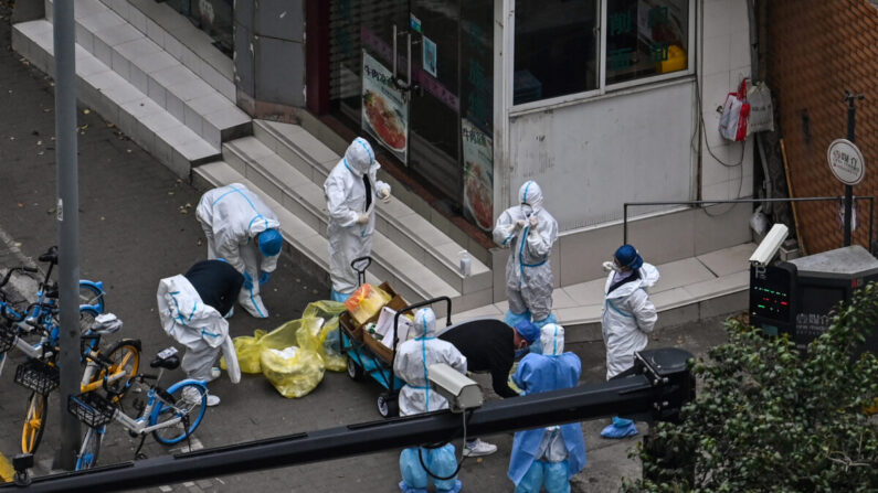 Los trabajadores se quitan el equipo de protección junto a la entrada de un barrio durante la segunda etapa de un confinamiento por la pandemia en el distrito de Jing'an, en Shanghai, el 5 de abril de 2022. (Hector Retamal/AFP vía Getty Images)