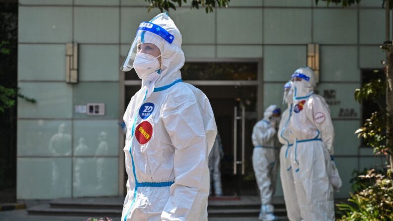 Trabajadores y voluntarios permanecen en un recinto donde se realizan pruebas de COVID-19 a los residentes durante la segunda fase de un cierre por pandemia en el distrito de Jing'an en Shanghai, China, el 6 de abril de 2022. (Hector Retamal/AFP vía Getty Images)