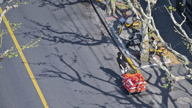 Un hombre tira de un carrito en una calle durante un cierre por el COVID-19 en el distrito de Jing'an en Shanghái el 8 de abril de 2022. (Hector Retamal/AFP vía Getty Images)