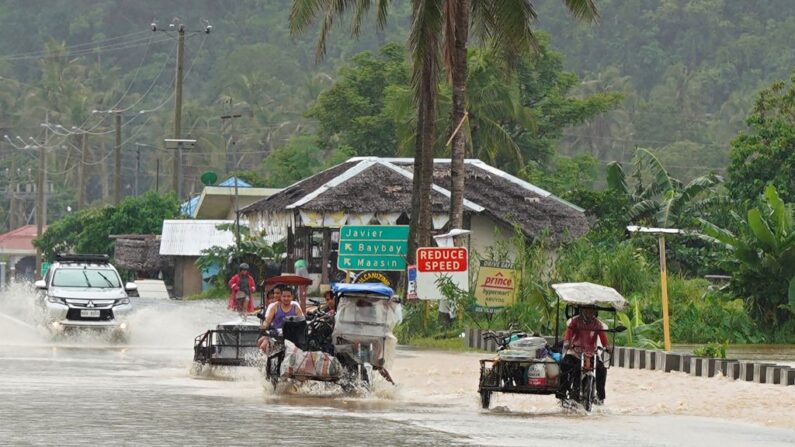 Los automovilistas vadean una carretera inundada tras las fuertes lluvias provocadas por la tormenta tropical Agaton en la ciudad de Abuyog, provincia de Leyte, sur de Filipinas, el 11 de abril de 2022. (Bobbie Alota/AFP vía Getty Images)