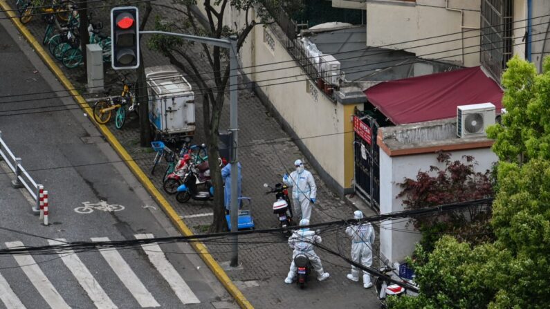 Policías con equipo de protección personal junto a la entrada de un barrio durante un cierre por COVID-19, en el distrito de Jing'an de Shanghái, el 15 de abril de 2022. (Hector Retamal/AFP vía Getty Images)
