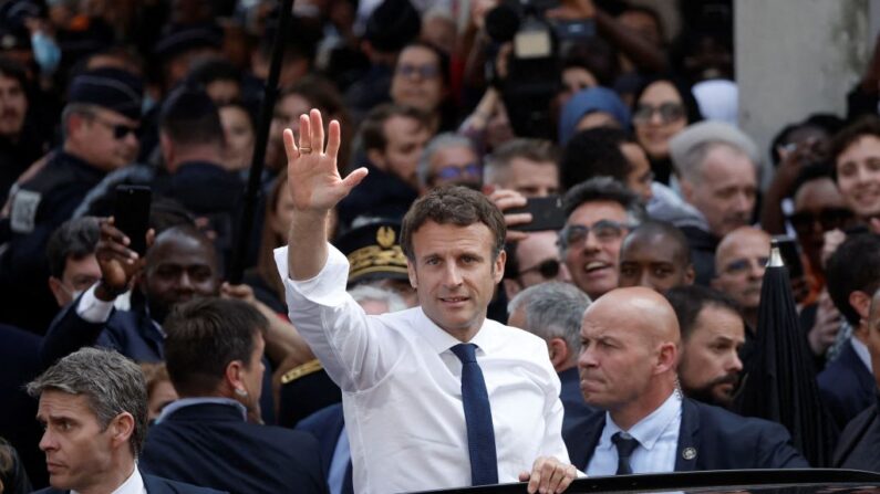 El presidente francés Emmanuel Macron saluda desde su coche al salir tras una visita en la plaza del mercado de Saint-Christophe en Cergy, suburbio de París, el 27 de abril de 2022, durante su primer viaje tras ser reelegido presidente. (Benoit Tessier/POOL/AFP vía Getty Images)