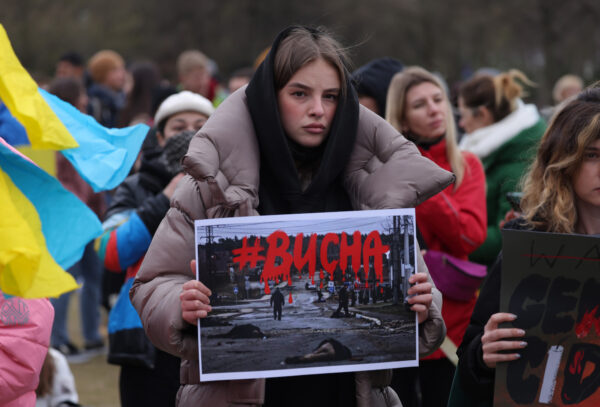 Una manifestante sostiene una fotografía que muestra a civiles asesinados de la ciudad ucraniana de Bucha, cerca de Kiev, durante una manifestación contra la invasión militar rusa a Ucrania, en Berlín, Alemania, el 6 de abril de 2022. (Sean Gallup/Getty Images)